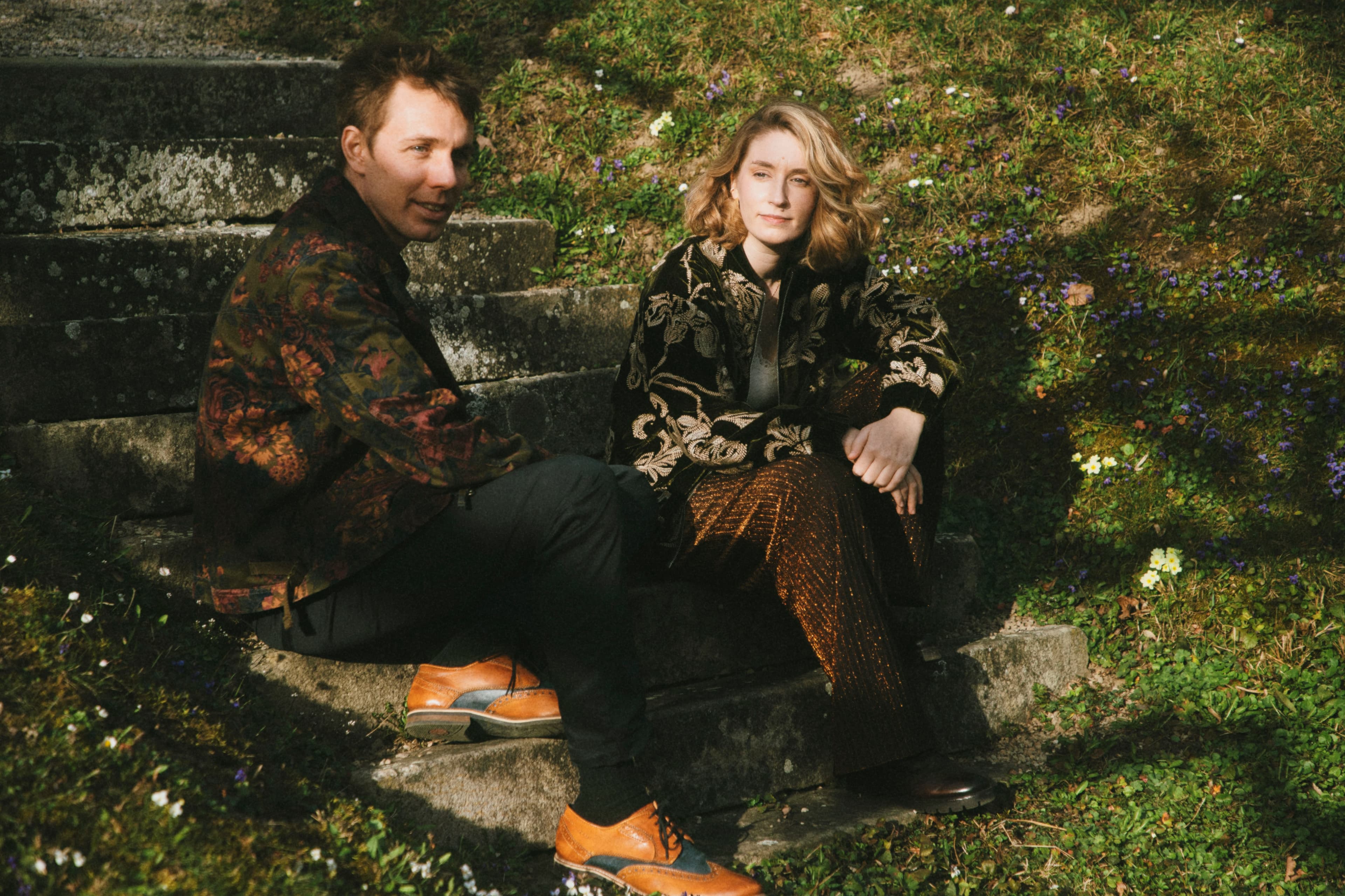 LISZ sitting on stone steps surrounded by wildflowers
